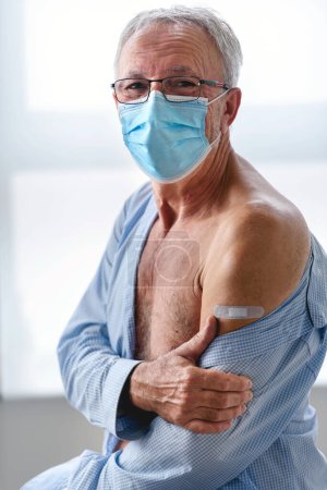 Photo for Elderly man with a disposable face mask, sitting after getting vaccinated - Royalty Free Image
