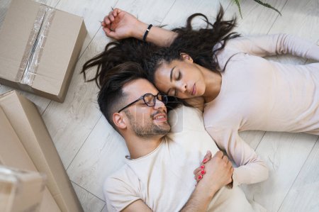 Téléchargez les photos : Jeune couple couché sur le sol dans leur nouvelle maison - en image libre de droit