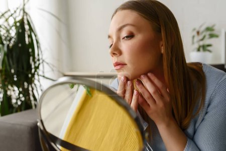 Foto de Joven mujer hermosa mirándose en el espejo en casa. Preocupado por el acné. Problemas con el acné. - Imagen libre de derechos