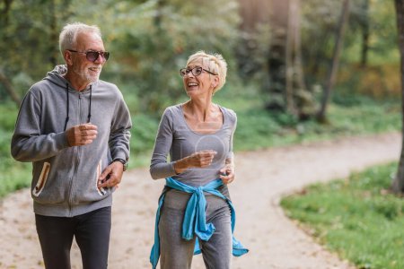 Fröhliches, aktives Seniorenpaar beim Joggen im Park. Gemeinsam Sport treiben, um das Altern zu stoppen.