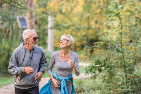 Téléchargez les photos : Joyeux, jogging de couple senior actif dans le parc. Faites de l'exercice ensemble pour arrêter le vieillissement. - en image libre de droit