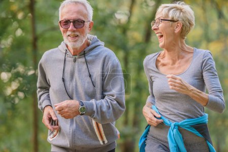 Photo for Cheerful, active senior couple jogging in the park. Exercise together to stop aging. - Royalty Free Image
