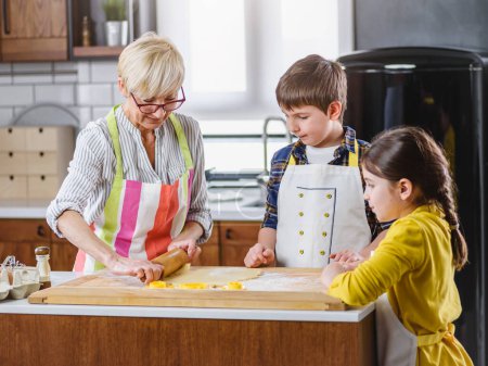 Téléchargez les photos : Grand-mère préparer des biscuits avec ses petits-enfants - en image libre de droit