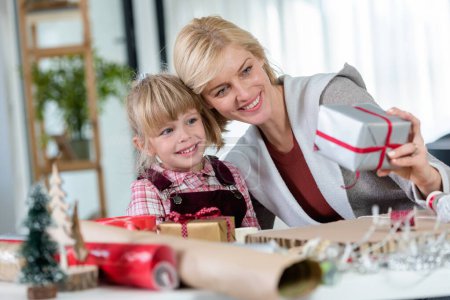 Photo for Mother and daughter preparing for holidays, wrapping gifts - Royalty Free Image