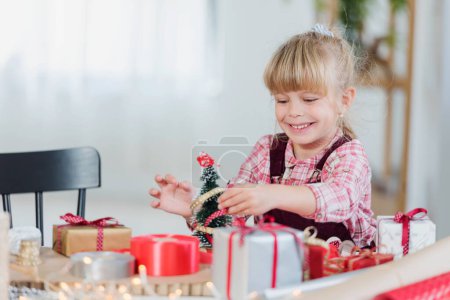 Téléchargez les photos : Petite fille jouant avec des décorations et des cadeaux de Noël - en image libre de droit