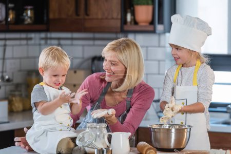 Foto de Feliz madre cocinando con hija e hijo - Imagen libre de derechos