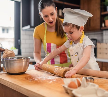 Téléchargez les photos : Mère cuisinant avec son fils. travailler avec la pâte - en image libre de droit