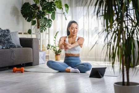 Foto de Joven mujer asiática instructora de yoga usando tableta pc en una clase de yoga en línea - Imagen libre de derechos