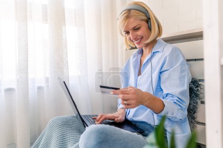 Photo for Young woman using a credit card at home to make a purchase or payment over the internet - Royalty Free Image
