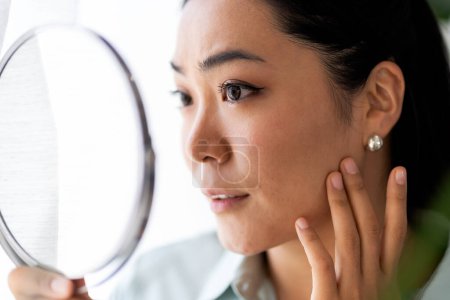 Téléchargez les photos : Jeune femme asiatique de l'Est se regardant dans le miroir. - en image libre de droit