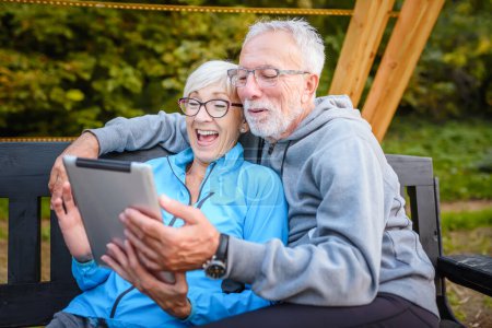 Foto de Feliz pareja de ancianos utilizando tableta al aire libre - Imagen libre de derechos