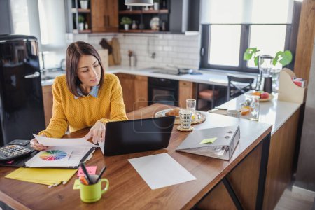 Téléchargez les photos : Femme indépendante travaillant au bureau à domicile avec un ordinateur portable. Espace de travail et temps de travail flexibles. - en image libre de droit