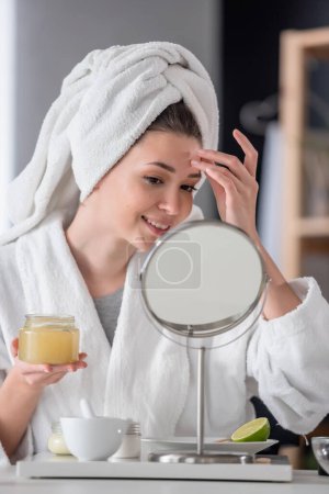 Photo for Beautiful young woman in bathrobe and towel looking at mirror, skincare concept - Royalty Free Image