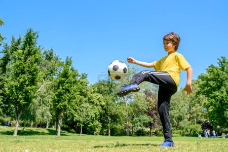Téléchargez les photos : Petit garçon footballeur sur un terrain - en image libre de droit