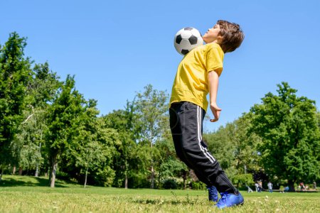 Téléchargez les photos : Petit garçon footballeur sur un terrain - en image libre de droit