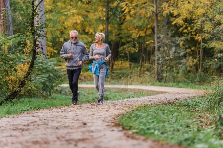 Téléchargez les photos : Heureux couple aîné jogging dans le parc - en image libre de droit