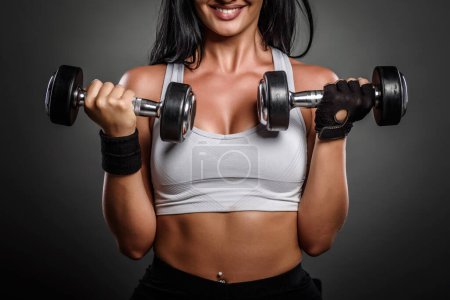 Photo for Young beautiful woman with dumbbells on dark background - Royalty Free Image