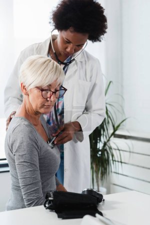 Foto de Médico afroamericano examinando mujer mayor paciente - Imagen libre de derechos