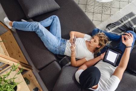 Téléchargez les photos : Couple se détendre dans le salon, en utilisant des gadgets - en image libre de droit