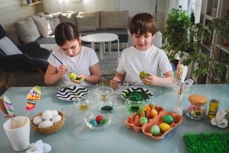 Téléchargez les photos : Frère et soeur se préparant à ester, peignant des œufs - en image libre de droit