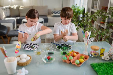 Téléchargez les photos : Frère et soeur se préparant à ester, peignant des œufs - en image libre de droit