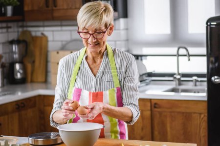Photo for Senior aged woman baking in home kitchen. - Royalty Free Image