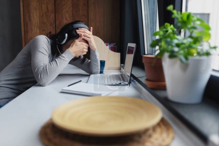 Foto de Mujer joven sentada frente a la computadora portátil en casa sintiéndose deprimida - Imagen libre de derechos