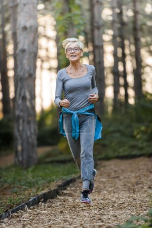 Foto de Mujer mayor sonriente corriendo en el parque. Actividades deportivas para personas mayores. - Imagen libre de derechos