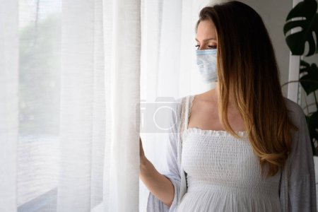 Foto de Hermosa mujer embarazada con máscara, de pie en el hospital - Imagen libre de derechos