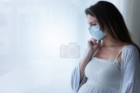 Foto de Hermosa mujer embarazada con máscara, de pie en el hospital - Imagen libre de derechos