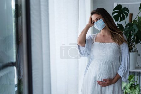 Photo for Beautiful pregnant woman wearing mask, standing in the hospital - Royalty Free Image