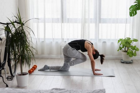 Téléchargez les photos : Jeune femme pratiquant l'exercice de yoga à la maison. Routines sportives quotidiennes pour un mode de vie sain et un soulagement du stress. - en image libre de droit