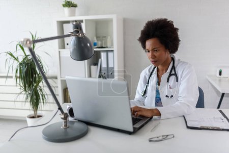 Téléchargez les photos : Femme médecin avec stéthoscope à son bureau travaillant dur - en image libre de droit