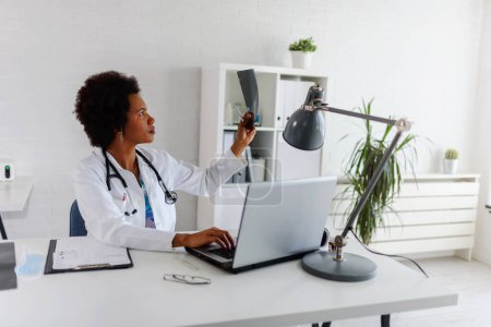 Téléchargez les photos : Femme médecin avec stéthoscope à son bureau travaillant dur - en image libre de droit