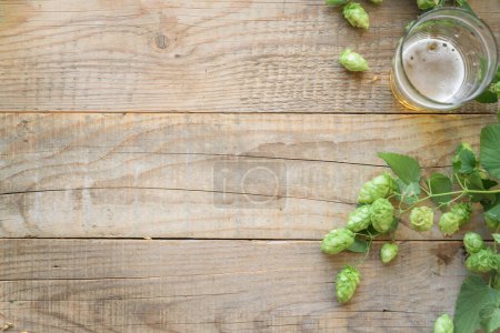 Photo for Green hop cones and glass of beer on wooden background - Royalty Free Image