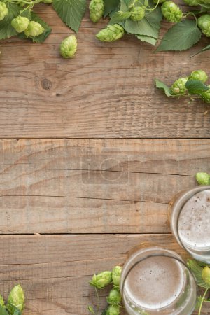 Téléchargez les photos : Houblon vert frais avec des verres de bière sur fond en bois - en image libre de droit