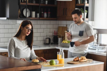 Photo for Smiling couple enjoying beautiful morning at home kitchen, having breakfast, drinking coffee and juice - Royalty Free Image