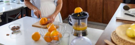 Foto de Mujer joven preparando jugo de naranja en la cocina - Imagen libre de derechos
