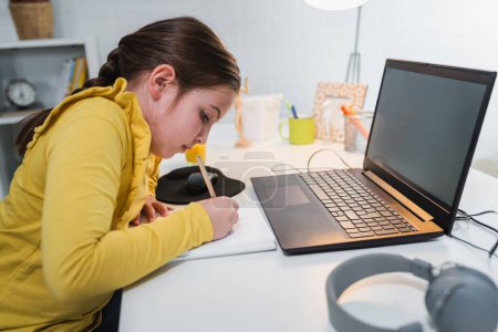 Téléchargez les photos : Fille utilise son ordinateur portable tout en étudiant, éducation en ligne - en image libre de droit