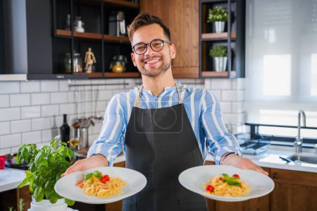 Foto de Joven chef sonriente mostrando pasta recién hecha en casa - Imagen libre de derechos