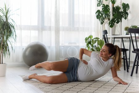 Foto de Hermosa mujer embarazada haciendo ejercicios en casa - Imagen libre de derechos