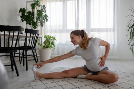 Téléchargez les photos : Belle femme enceinte faisant des exercices à la maison - en image libre de droit