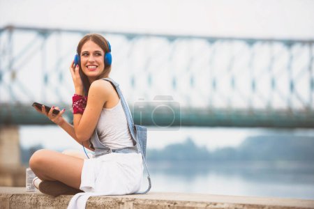 Téléchargez les photos : Belle jeune femme à l'écoute de la musique dans les écouteurs - en image libre de droit