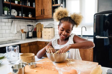 Téléchargez les photos : Heureux afro-américaine fille faire des cookies à la cuisine - en image libre de droit