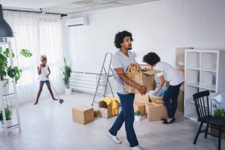 Photo for Happy playful African American family moving in new apartment, unpacking, moving stuff, purchase property concept - Royalty Free Image