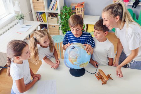 Foto de Grupo de niños y maestro en geografía de aprendizaje en el aula - Imagen libre de derechos