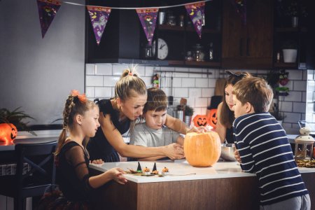 Téléchargez les photos : Concept halloween, femme avec enfants sculptant lanterne de citrouille - en image libre de droit