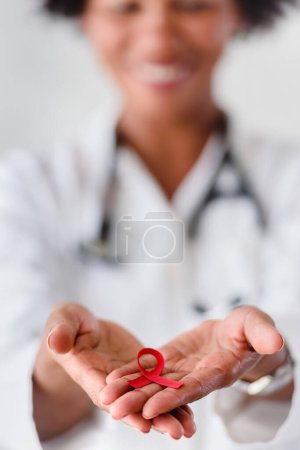 Téléchargez les photos : Ruban rouge, aide à la sensibilisation. dans les mains des médecins - en image libre de droit