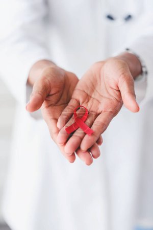 Photo for Red ribbon, aids awareness. in doctors hands - Royalty Free Image