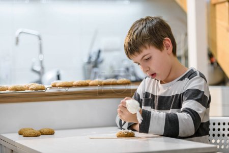 Téléchargez les photos : Mignon petit garçon décoration cookies avec glaçage - en image libre de droit